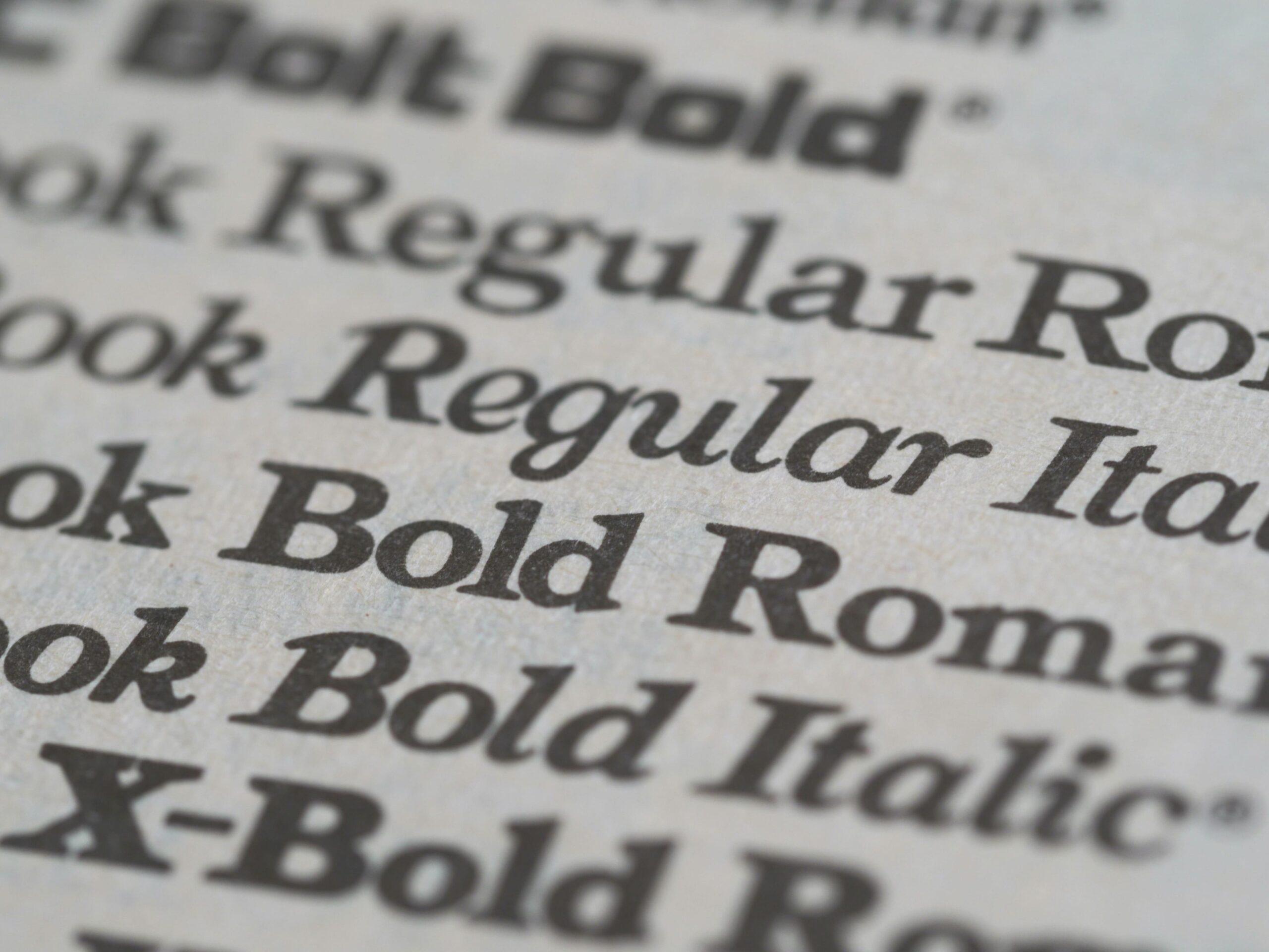 Close-up of printed font styles such as Regular, Italic, Bold, and Roman, illustrating different typefaces—relevant to understanding typography licenses and proper font usage.