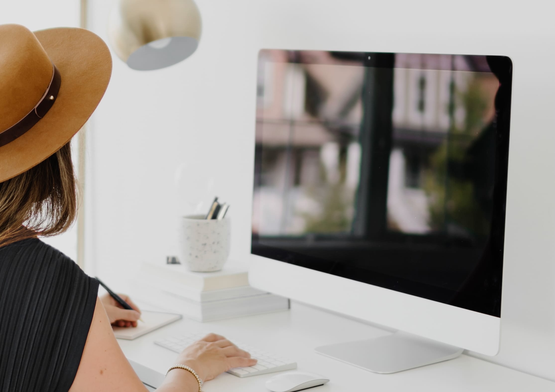 Woman working at a bright, modern desk with a large desktop computer, searching for visual content—symbolizing the process of finding professional images for a wellness website.